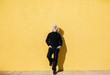© Guille Faingold/Stocksy - Stylish old gentleman laughing against yellow