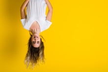 Beautiful Young Blonde Woman Jumping Happy And Excited Hanging Upside Down Over Isolated Yellow Background