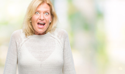 Canvas Print - Middle age blonde woman wearing winter sweater isolated background afraid and shocked with surprise expression, fear and excited face.