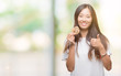 © Krakenimages.com - Young asian woman eating chocolate chip cookie over isolated background happy with big smile doing ok sign, thumb up with fingers, excellent sign