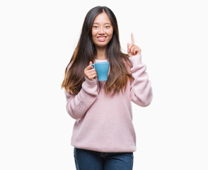 Sticker - Young asian woman drinking coffee over isolated background surprised with an idea or question pointing finger with happy face, number one