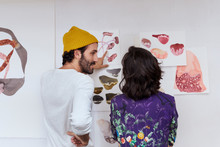 Artists Communicating Over Illustrations Stuck On Wall