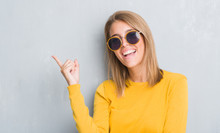 Beautiful Young Woman Standing Over Grunge Grey Wall Wearing Retro Sunglasses Very Happy Pointing With Hand And Finger To The Side