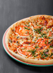 Canvas Print - Pizza with chicken, tomatoes, mushrooms, greens and cheese on dark wooden background. Homemade pizza