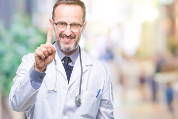 Poster - Middle age senior hoary doctor man wearing medical uniform isolated background showing and pointing up with finger number one while smiling confident and happy.