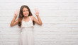 © Krakenimages.com - Young hispanic kid over white brick wall showing and pointing up with fingers number nine while smiling confident and happy.