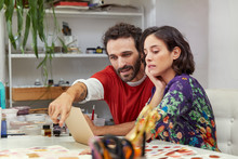 Artist Pointing At Illustration While Using Laptop With Woman