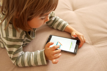 Cute kid girl play game on smart phone