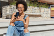 © WHstudio Leushin N - Satisfied blogger texts funny message for post on personal website, dressed in ragged overalls, sends feedback, downloads file, wears eyewear, poses at city steps, copy space for your advertising text