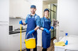 © rh2010 - Portrait of a couple as a professional cleaners in uniform standing together with cleaning tools indoors