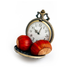 Vintage antique pocket watch with roasted chestnuts, isolated on white background. Street food business, time is money concept.