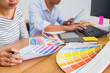 © MIND AND I - Graphic design with color swatches and tablet on a desk. Graphic designer drawing something on tablet at the office with work tools and accessories.