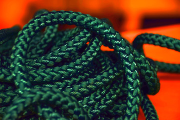 synthetic rope close up in front of orange background, new green rope macro shot for the shipping or health or sports industry