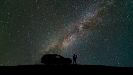 Wall Mural - The couple standing near a car against sky with stars. time lapse