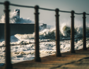 lighthouse with a big wave of water from the ocean with blu sky