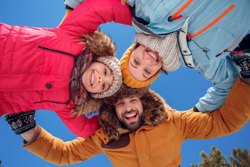 Winter vacation. Family time together outdoors hugging looking camera smiling cheerful bottom view close-up