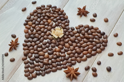Foto Heart of coffee beans with star of anise and satin in pastel shades of a rose on a light wooden background