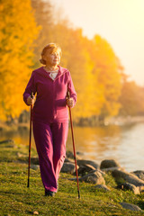 Active senior woman hiking walks at colorful Sunny autumn park