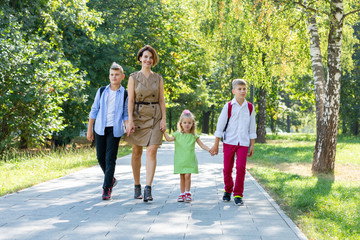 Happy young family, mother with three children walking in the park. Healthy lifestyle concept