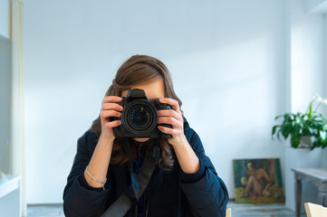 Young man photographer making selfie at mirror. Focus on camera lens.