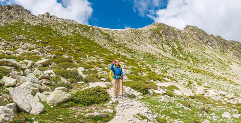 Wall Mural - Happy woman hiker travels in Pyrenees Mountains in Andorra and Spain. Nordic walking, recreation and trekking along GR11 path trail