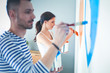 © lenets_tan - Portrait of happy smiling young couple painting interior wall of new house. young couple