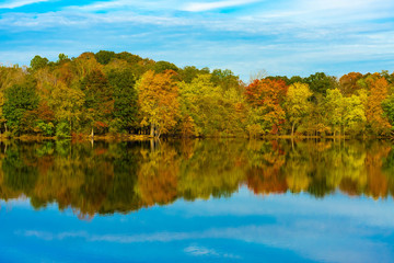 Canvas Print - Colorful fall trees reflecting on calm water in park