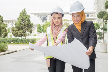 Professional woman engineers are discussing on construction at outdoor.