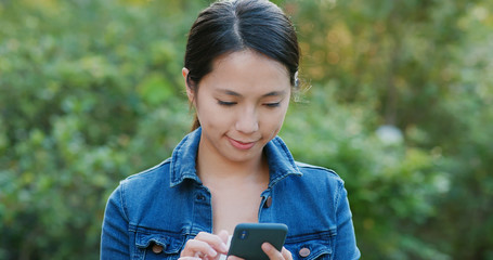 Poster - Woman check on mobile phone in the city park under sunlight