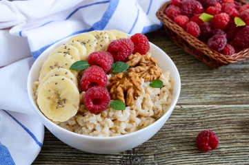 Wall Mural - Delicious and healthy oatmeal with banana, raspberries, nuts. Healthy breakfast. Fitness food. Proper nutrition.