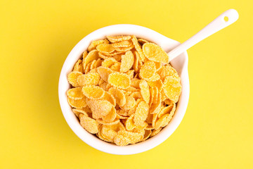 Crispy corn flakes in clay bowl on bright yellow background