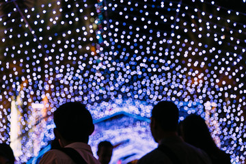 Wall Mural - Lights bokeh with blur people in foreground. Festival for Christmas and Happy New Year celebration.