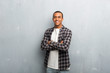 © luismolinero - Young african american man with checkered shirt keeping the arms crossed in frontal position
