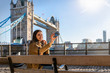 canvas print picture - Touristin auf einer Sightseeing Tour vor der Tower Bridge in London macht ein Selfie von sich mit Ihrem Handy
