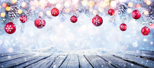 Wall Mural - christmas table with red hanging balls in snowy background