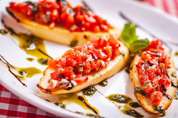 Poster - Traditional Italian bruschetta with cherry tomatoes, pesto sauce and balsamic vinegar on white plate. Close up