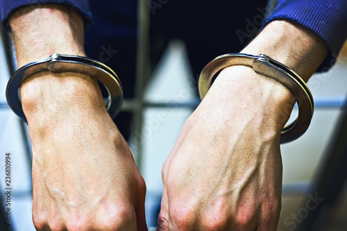 Fotografia Male hands in metal handcuffs closeup