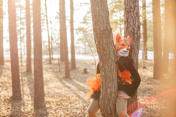 Beautiful girl model in fox mask park outdoor. Fashion woman with an unusual strange appearance. Non-standard creative thinking