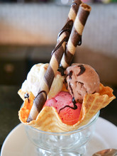 Mixed Ice Cream Scoops In Wafer Bowl. Dessert Sundae With Neapolitan Flavors Of Ice Cream - Glass Dish With Scoops Of Chocolate, Vanilla, And Strawberry Ice Cream With Rolled Cookie Biscuits And