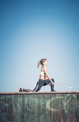 Wall Mural - Pretty woman performs exercising outdoors in the park.