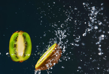 Wall Mural - Kiwi slices in drops and splashes of water