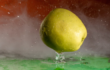 Wall Mural - Green apple and splashes of water on a colored background