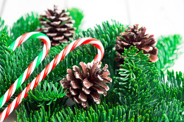 Christmas tree branches with candy canes on white wooden desk. Flat lay space for text.