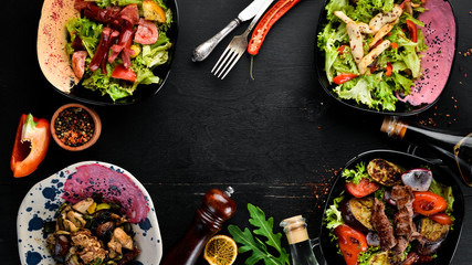 Background of food and dishes. Meat and fish dishes, and salad. On a wooden background. Top view. Free space for your text.