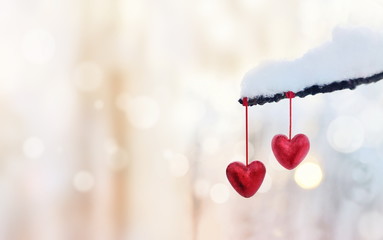 Red hearts on snowy tree branch in winter. Holidays happy valent