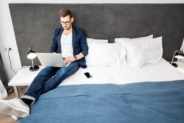 businessman dressed casually working with laptop at the hotel room or bedroom