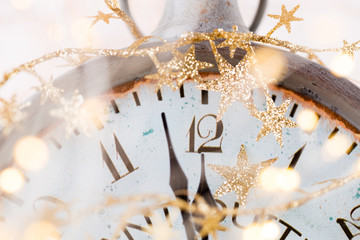 vintage alarm clock is showing midnight. It is twelve o'clock, christmas and bokeh, holiday happy new year festive concept on light bokeh background