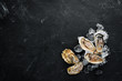 Oysters with ice and lemon on black stone background. Seafood. Top view. Free copy space.