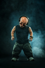 Wall Mural - Portrait of stylish midget MC in with headphones and sunglasses posing with microphone.