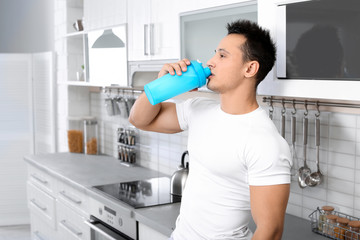 Poster - Young man drinking protein shake in kitchen